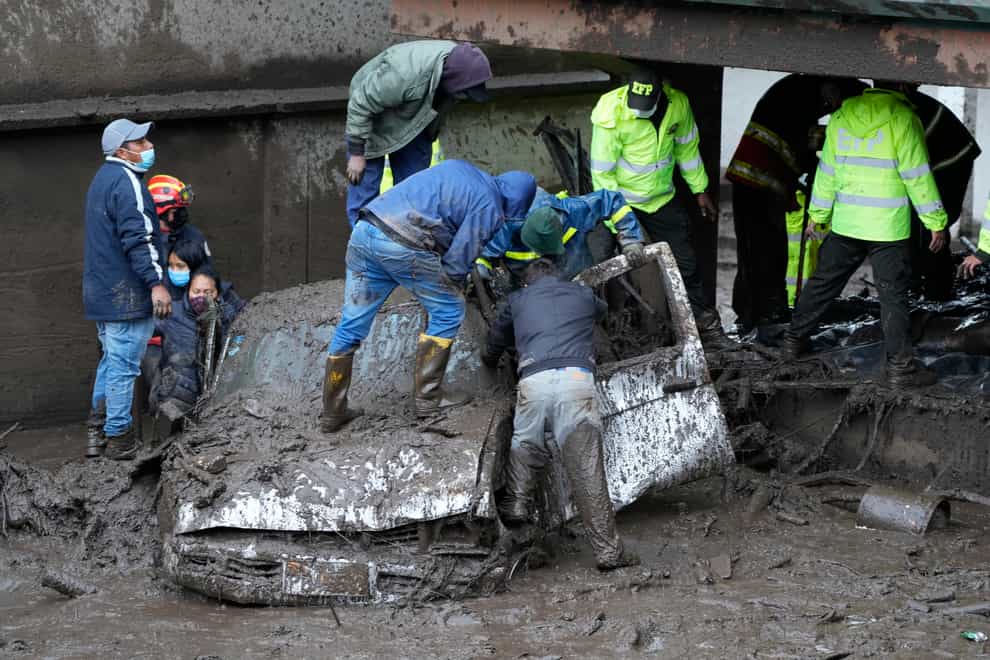 Residents and rescue workers search for people inside a car after a rain-weakened hillside collapsed and brought waves of mud over La Gasca area of Quito, Ecuador, Tuesday, Feb. 1, 2022. (AP Photo/Dolores Ochoa)