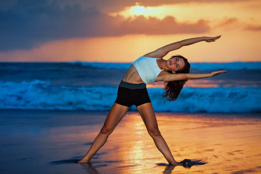 young woman doing exercise on the beach (Alamy/PA)