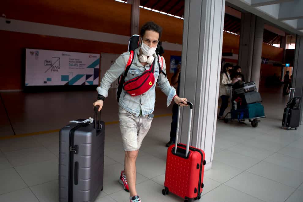 A Russian tourist carries his luggage upon his arrival at Bali’s international airport (Firdia Lisnawati/AP)