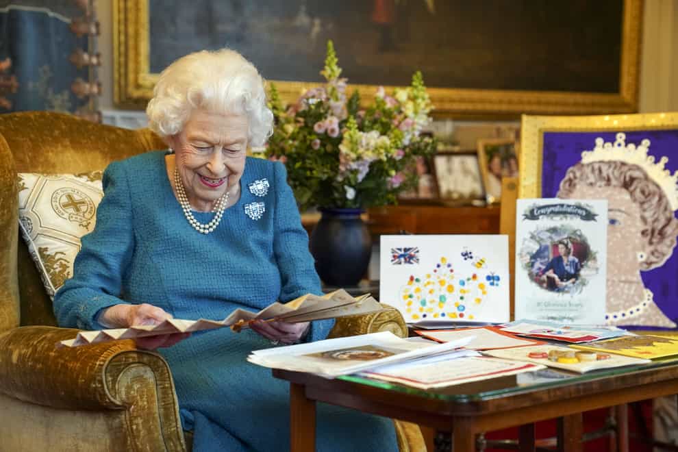 The Queen looks at a fan as she views a display of memorabilia from her Golden and Platinum Jubilees (PA)