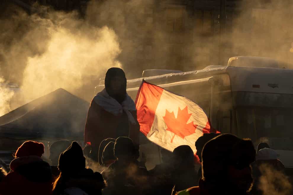 A protester stands on a barricade as trucks continue to block the city centre in protest of Covid-19 restrictions, in Ottawa (The Canadian Press via AP)