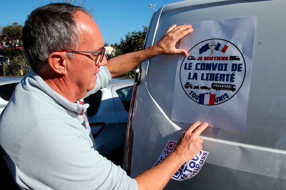 A man puts a poster reading Liberty Convoy on a van before leaving for Paris (Bob Edme/AP)