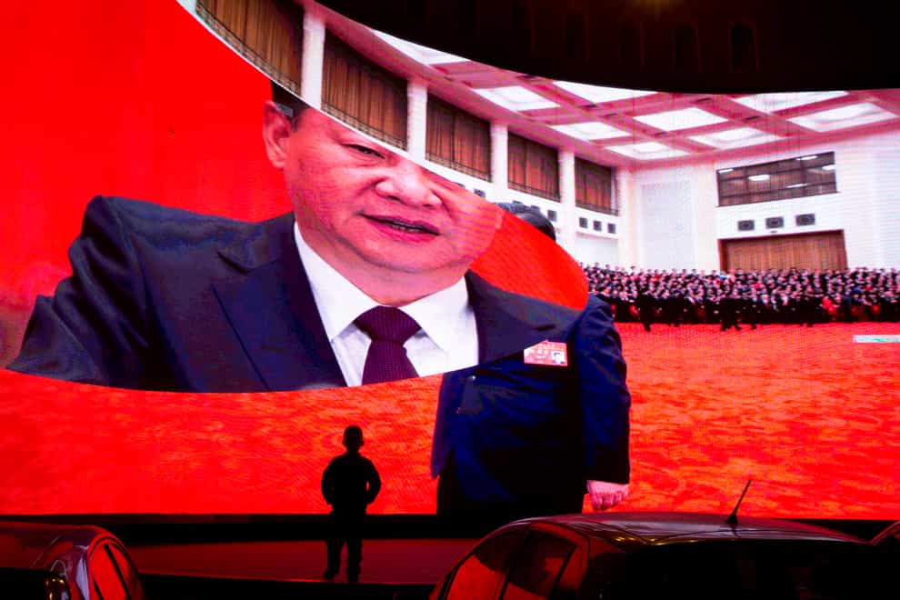 A child stands near a large screen showing photos of Chinese President Xi Jinping near a car park in Kashgar in western China’s Xinjiang region (AP Photo/Ng Han Guan)