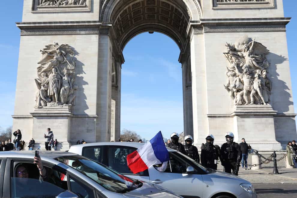 Protesters drive past the Arc de Triomphe on the Champs-Elysees Avenue in Paris (Adrienne Surprenant/AP)