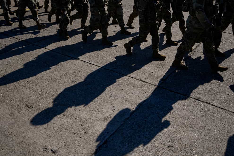 US soldiers cast shadows while walking during the visit of NATO Secretary General Jens Stoltenberg at the Mihail Kogalniceanu airbase, near the Black Sea port city of Constanta, eastern Romania, Friday, Feb. 11, 2022. Stoltenberg paid an official visit to Romania on Friday, where he joined the country’s president Klaus Iohannis at a military airbase that will host some of the 1,000 U.S. troops deployed to the country as the alliance bolsters its forces on the eastern flank as tensions soar between Russia and Ukraine. (AP Photo/Andreea Alexandru)