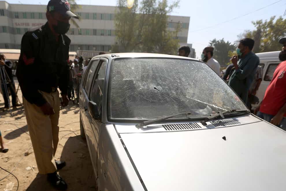 A police officer examines a bullet-riddled car of TV producer Athar Mateen (AP)