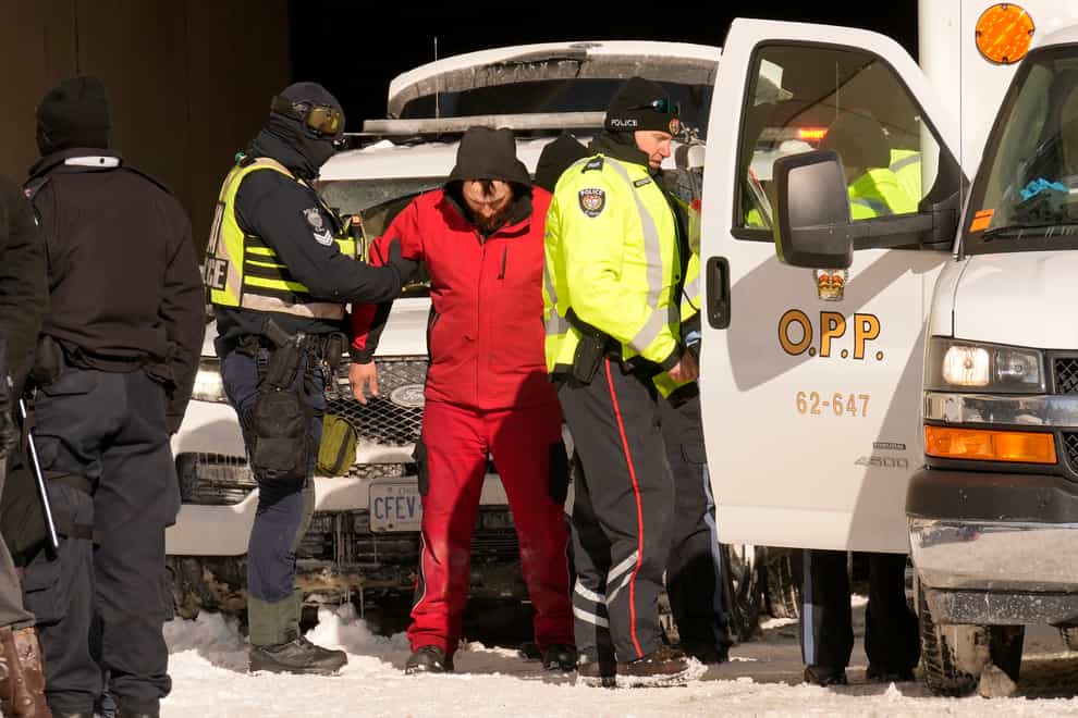 Police arrest a demonstrator as they work to bring a protest, which started in opposition to mandatory Covid-19 vaccine mandates and grew into a broader anti-government demonstration and occupation, to an end, in Ottawa, Ontario (Adrian Wyld/The Canadian Press via AP)