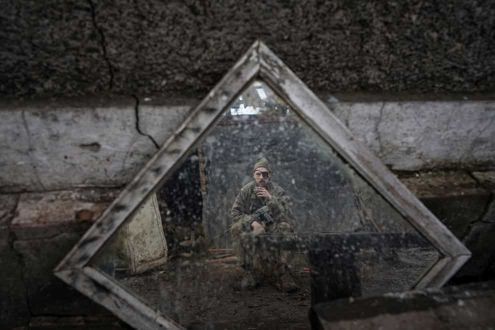 A Ukrainian serviceman is reflected in a mirror as he smokes a cigarette on a position at the line of separation between Ukraine-held territory and rebel-held territory near Zolote, Ukraine (AP Photo/Evgeniy Maloletka)