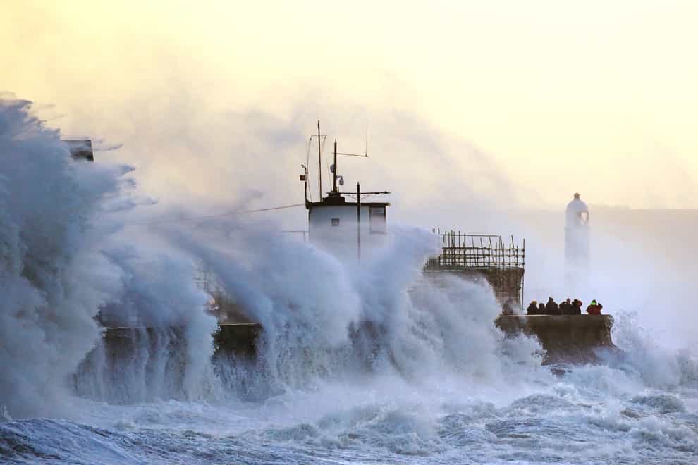 Waves crash against the sea wall and Porthcawl Lighthouse in Porthcawl, Bridgend, Wales (Jacob King/PA)