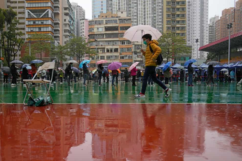 Residents line up to get tested for coronavirus at a temporary testing centre despite the rain in Hong Kong (Kin Cheung/AP)