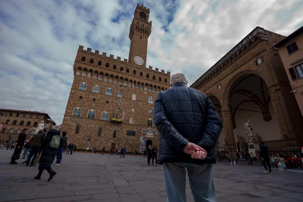 An elderly man looks at Florence’s 14th-century town hall Palazzo Vecchio (AP)