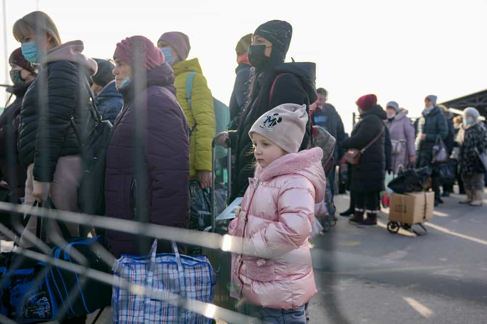 A little girl waits along with people crossing to Ukrainian government controlled areas from pro-Russian separatists controlled territory in Stanytsia Luhanska, the only crossing point open daily, in the Luhansk region, eastern Ukraine, Tuesday, Feb. 22, 2022. Russian lawmakers on Tuesday authorized President Vladimir Putin to use military force outside the country — a move that could presage a broader attack on Ukraine after the U.S. said an invasion was already underway there. (AP Photo/Vadim Ghirda)