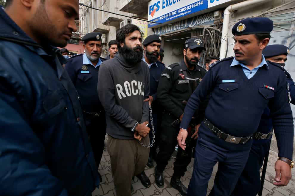 Police officers escort Zahir Jaffar, centre, for a court appearance in Islamabad, Pakistan (Anjum Naveed/AP)