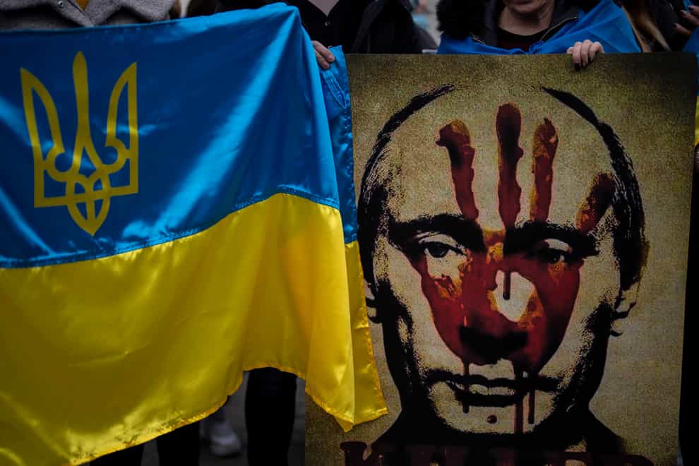 A protestor holds a banner depicting Russian President Vladimir Putin during a demonstration in front of the Russian Embassy in Madrid, Spain, Thursday, Feb. 24, 2022, after Russia’s attack on Ukraine. Russia launched a wide-ranging attack on Ukraine on Thursday, hitting cities and bases with airstrikes or shelling, as civilians piled into trains and cars to flee. (AP Photo/Manu Fernandez)