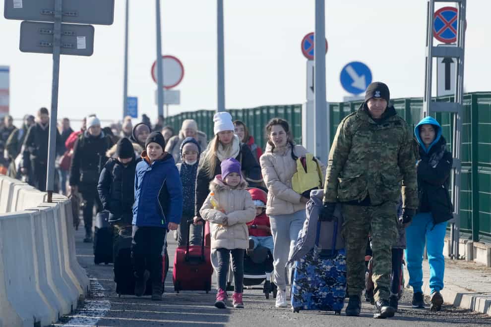 A Polish border guard assists refugees from Ukraine as they arrive to Poland at the Korczowa border crossing, Poland, Saturday, Feb. 26, 2022. (AP Photo/Czarek Sokolowski)