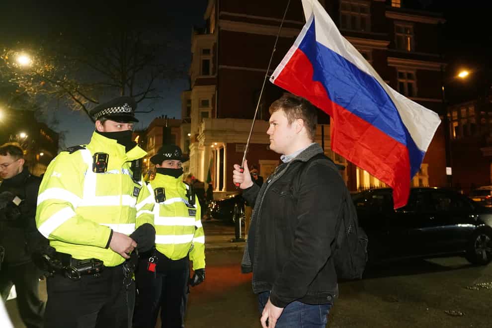 A police officer speaks to a man carrying the flag of Russia (Ian West/PA)