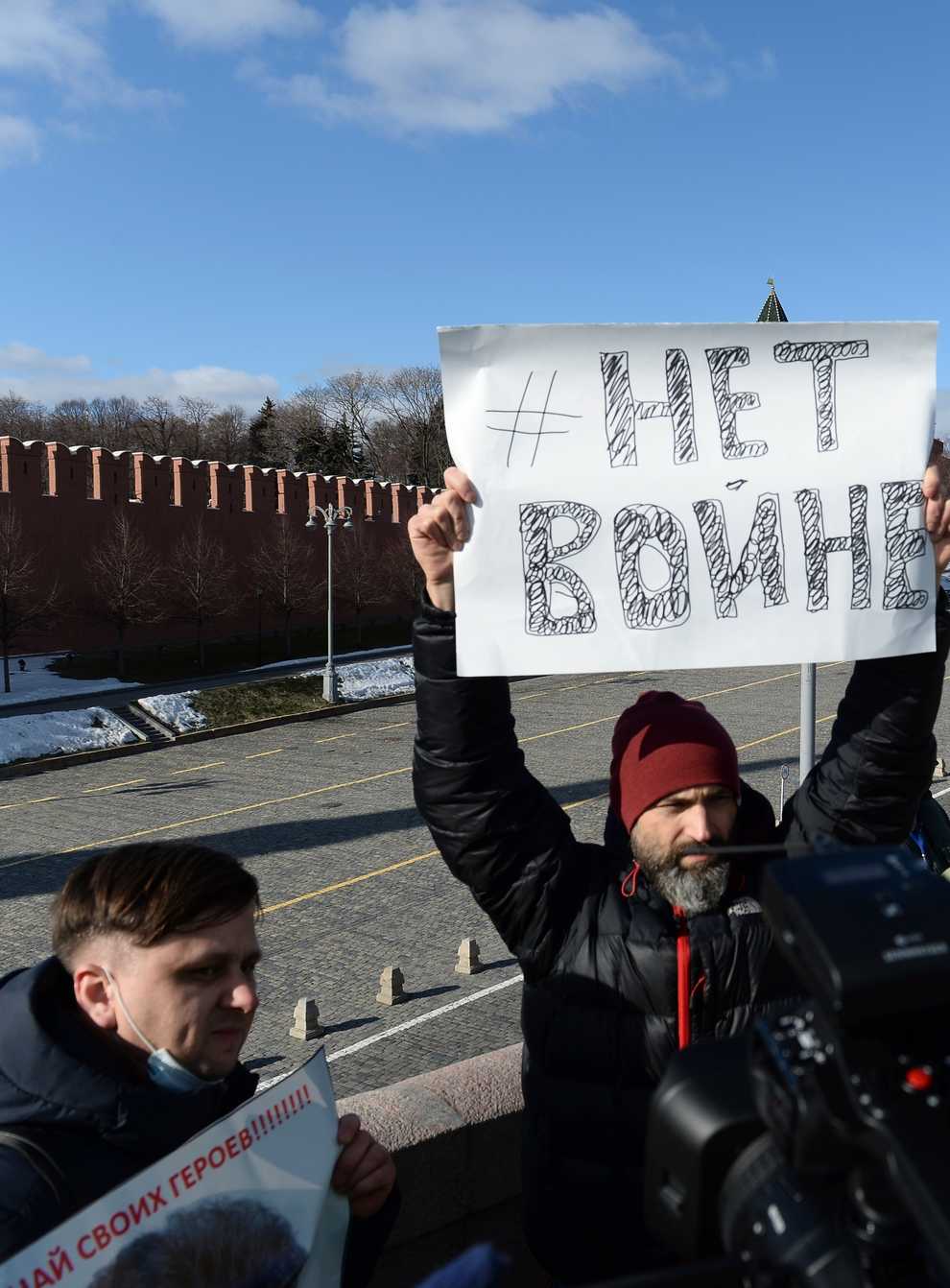 A man holds a poster which reads ‘No war’ as people lay flowers near where Russian opposition leader Boris Nemtsov was gunned down in Moscow, Russia (Denis Kaminev/AP)