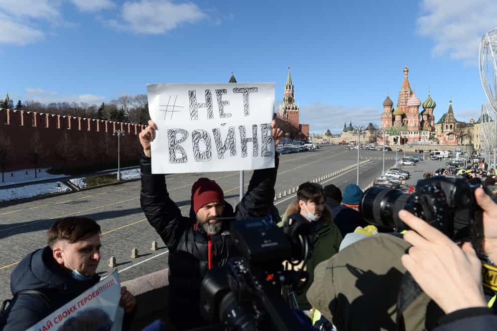 A man holds a poster which reads ‘No war’ as people lay flowers near where Russian opposition leader Boris Nemtsov was gunned down in Moscow, Russia (Denis Kaminev/AP)