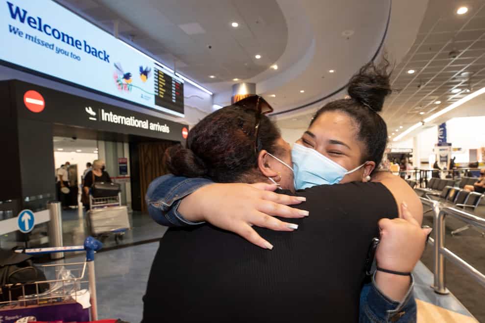 Two women embrace after one arrives on a flight from Australia at Auckland International Airport in Auckland (New Zealand Herald via AP)