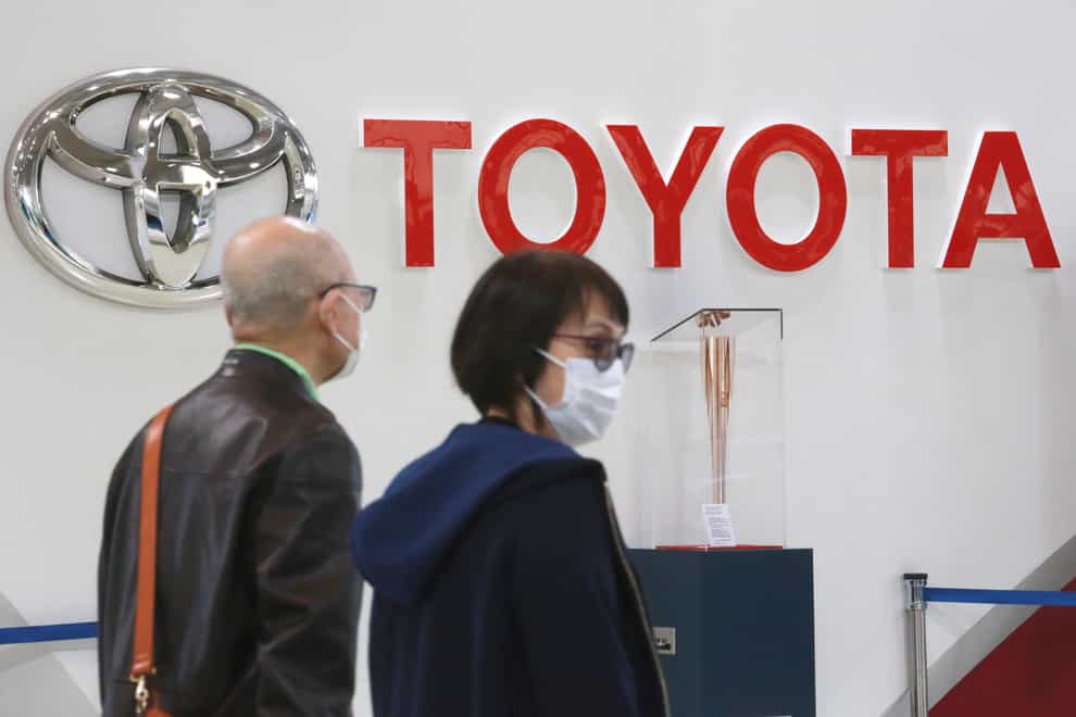 People walk past the logo of Toyota at a showroom in Tokyo (Kohi Sasahara/AP)
