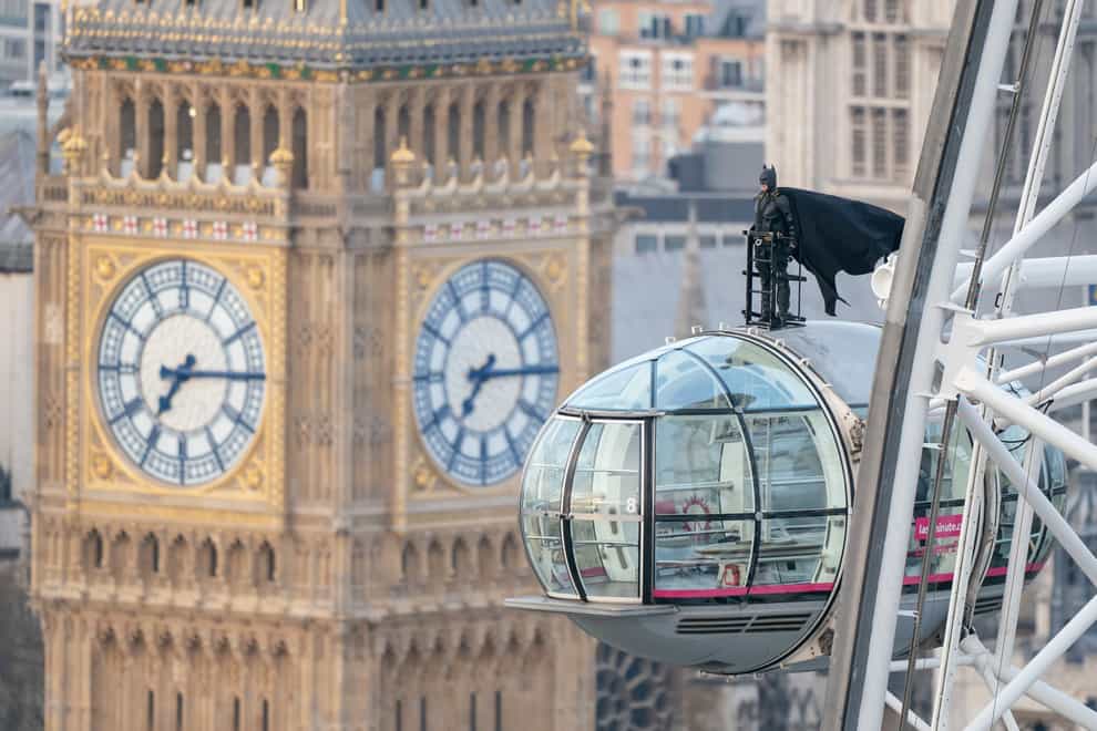 A man dressed as Batman stands on top of the London Eye, with the newly refurbished Big Ben in the background (Dominic Lipinski/PA)