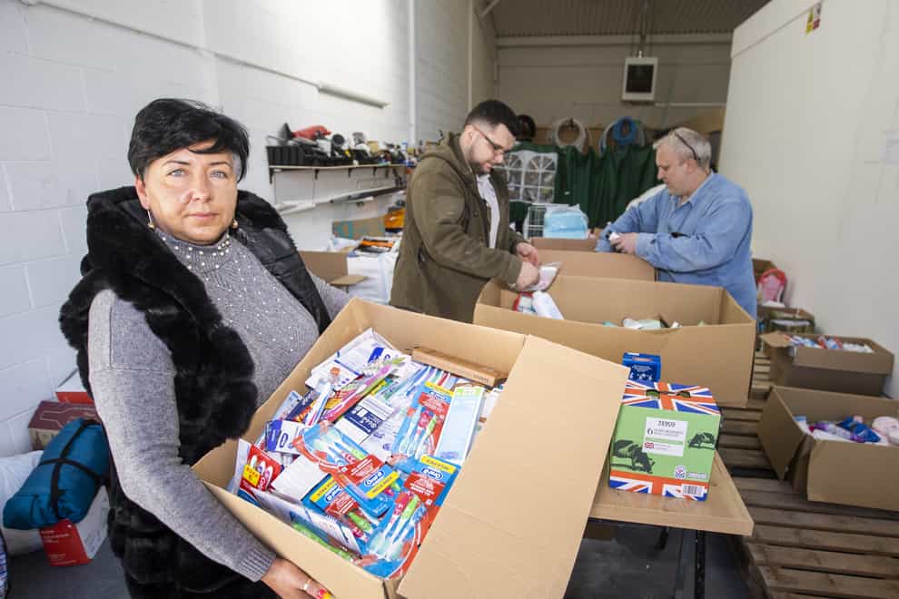 Kinga Orkisz with her husband Paul and son Konrad, who moved to Northern Ireland 16 years ago from Poland, sort supplies at their south Belfast business unit on Apollo Road to be sent to help the Ukrainian people (PA)