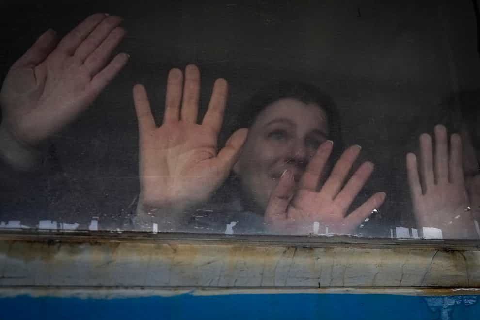People leaving their relatives press their palms against a window of a Lviv bound train, on the platform in Kyiv, Ukraine (Vadim Ghirda/AP)