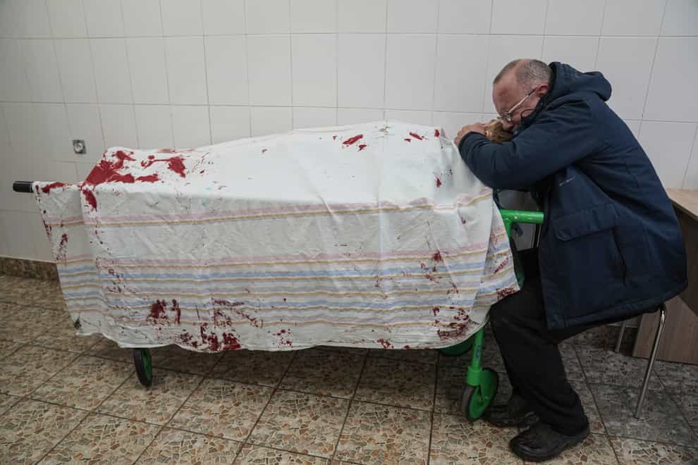 Serhii, father of teenager Iliya, cries on his son’s lifeless body lying on a stretcher (Evgeniy Maloletka/AP)