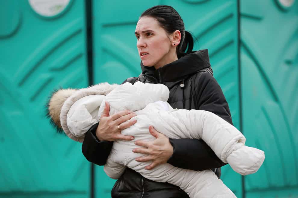 A woman fleeing Ukraine, holds a baby as they arrive at the border crossing in Medyka, Poland (Visar Kyreziu/AP)