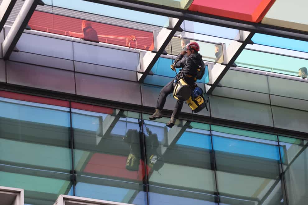 A specialist police team abseils down the Defra building in Westminster after activists from Animal Rebellion climbed the outside in protest (James Manning/PA)