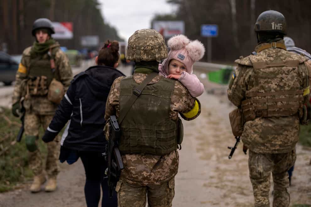 A Ukrainian soldier carries a baby fleeing with her family (Emilio Morenatti/AP)