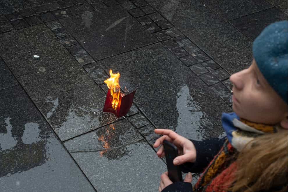 A Russian passport burns on the street during a protest against the Russian military invasion of Ukraine, in Belgrade, Serbia, on Sunday March 6 2022 (Marko Drobnjakovic/AP)