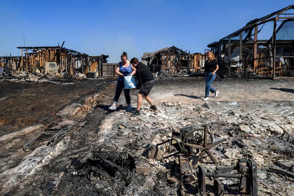 Emily Homeric, Robert O’Connor and Wandi Blanco pour water on hotspots behind homes in Panama City on Saturday March 5 2022 (Mike Fender/News Herald/AP)