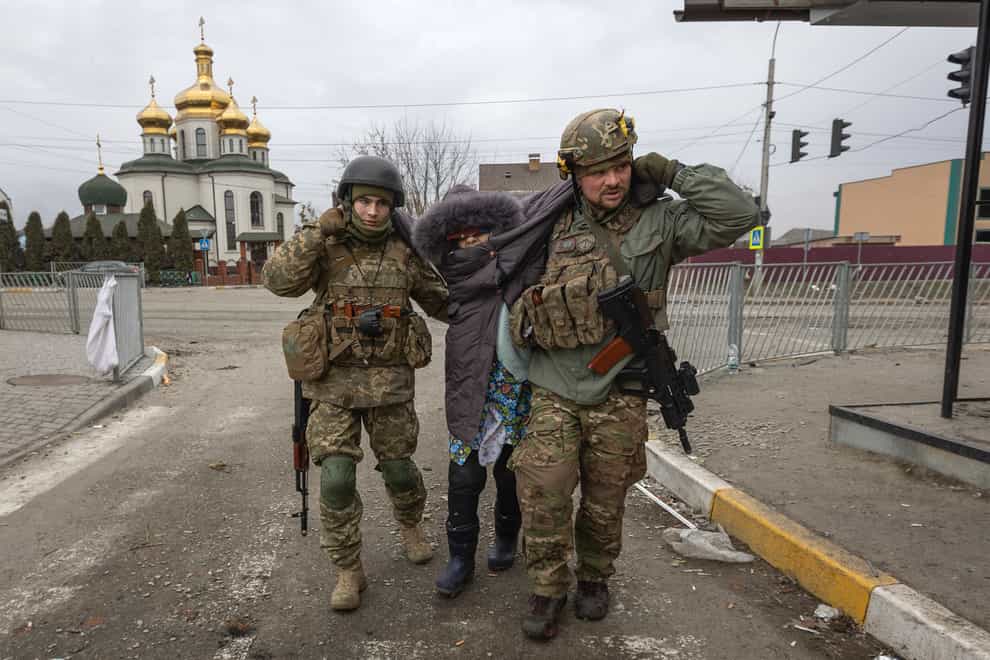 Ukrainian servicemen help an elderly woman, in the town of Irpin (Andriy Dubchak/AP)
