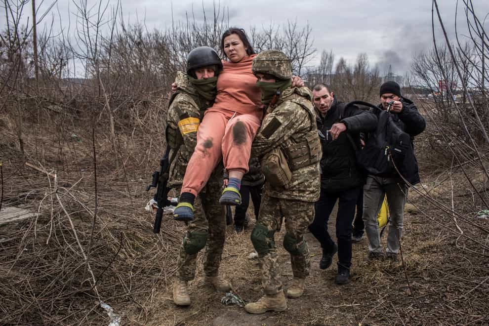 A woman carried by Ukrainian soldiers crosses an improvised path while fleeing the town of Irpin (Oleksandr Ratushniak/AP)