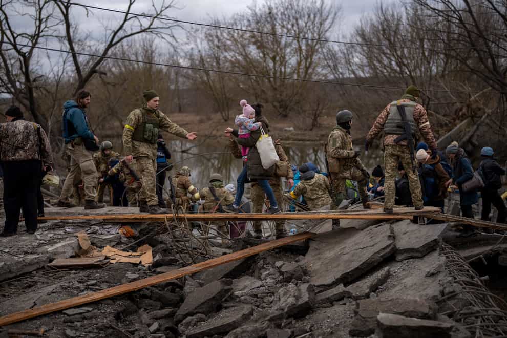 Ukrainian soldiers help a fleeing family crossing the Irpin river (Emilio Morenatti/AP)