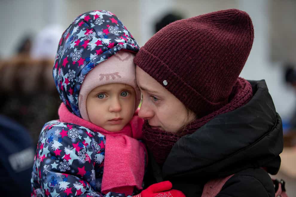 A mother and her child, fleeing Ukraine, wait to board a bus at the border crossing in Medyka, Poland (AP)