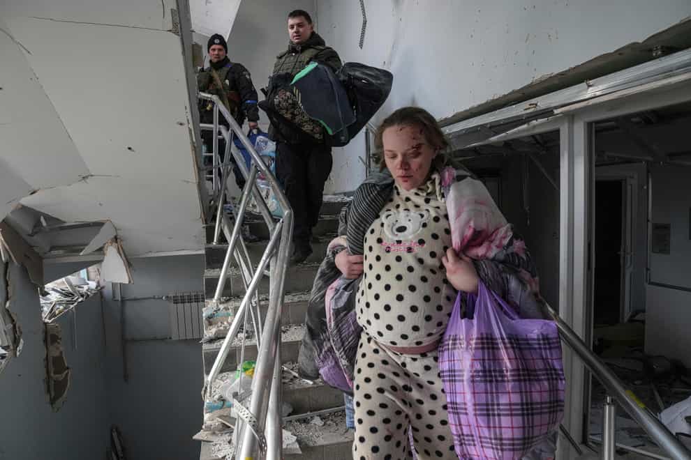 An injured pregnant woman walks downstairs in a maternity hospital damaged by shelling in Mariupol, Ukraine (AP Photo/Evgeniy Maloletka)