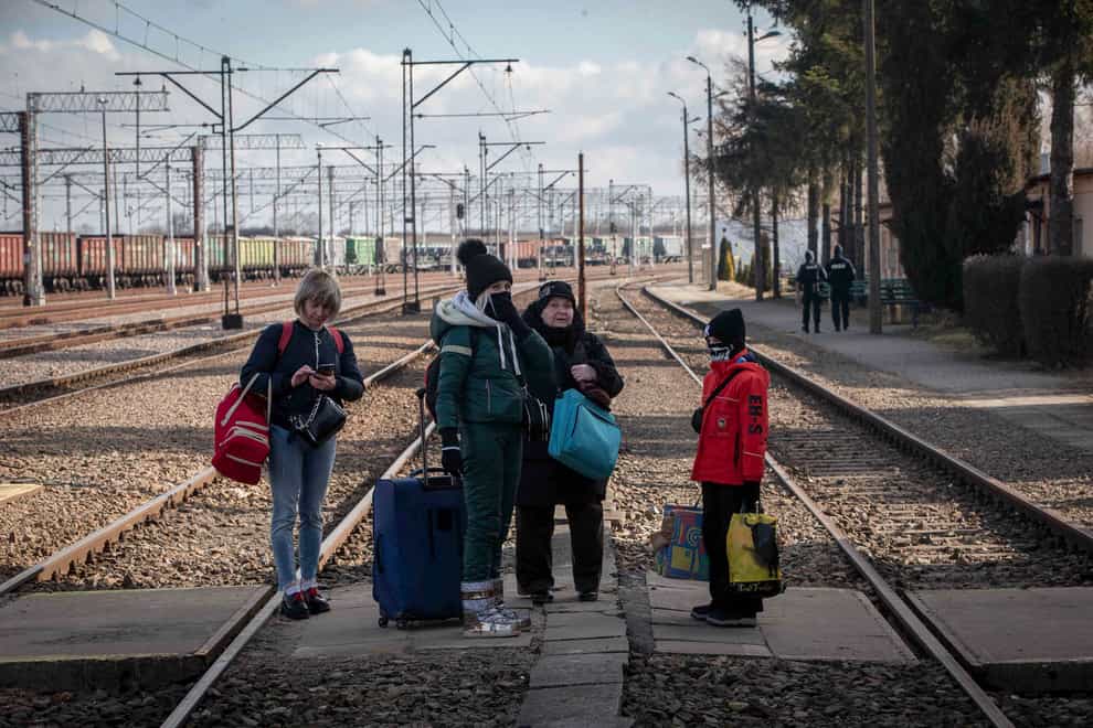 A family fleeing from Ukraine wait for the train at a border crossing station in Poland (Visar Kryeziu/AP)