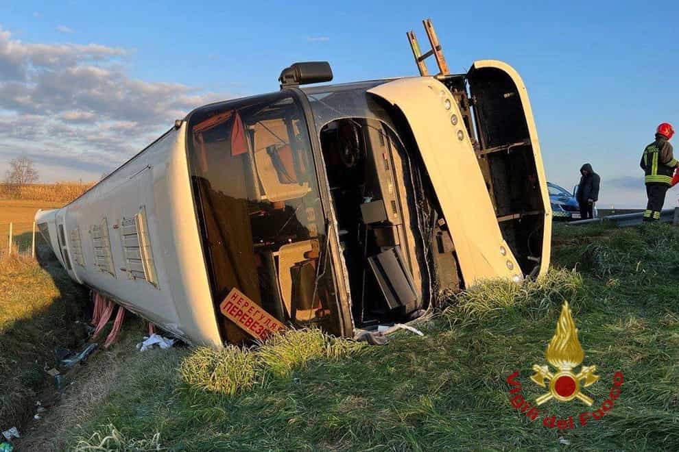 The bus lies on its side after overturning near Forli, Italy (Vigili del Fuoco/AP)
