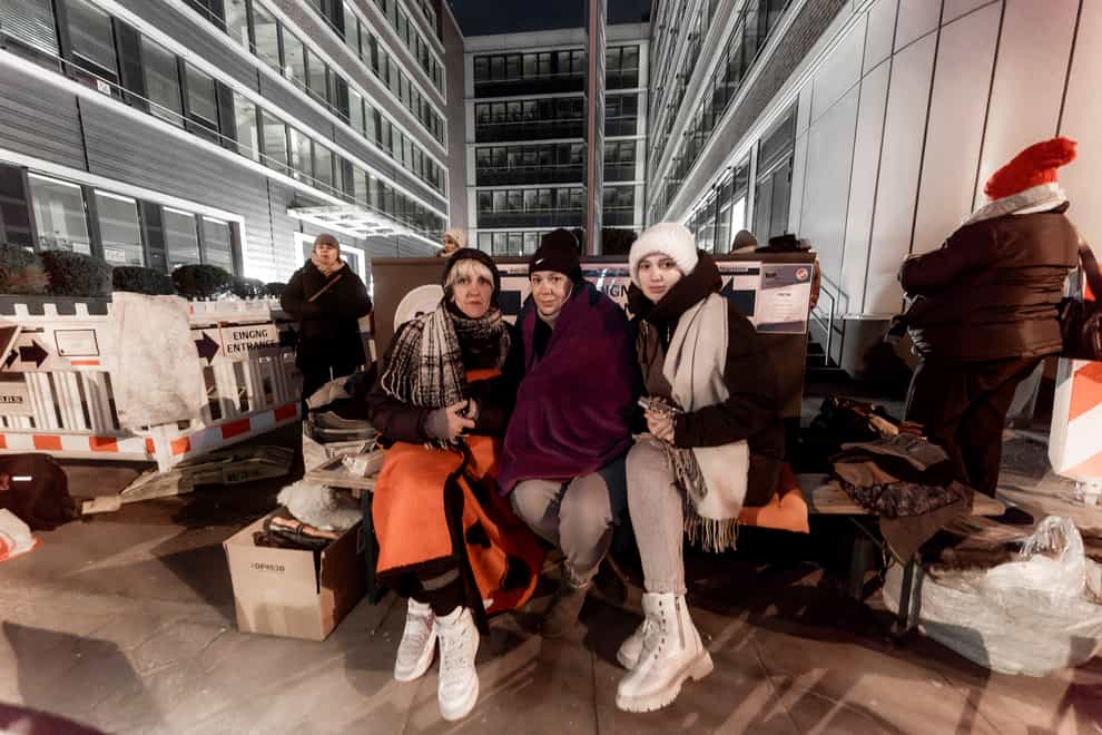Three women from Ukraine wait in front of the Hammer Strasse registration office in Hamburg (Markus Scholz/dpa via AP/PA)