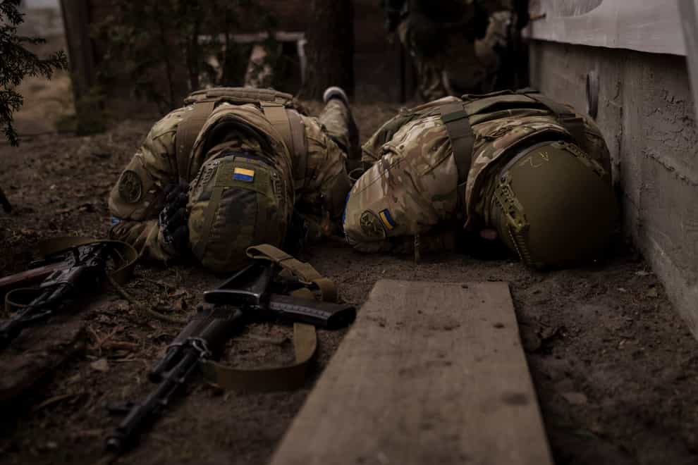Ukrainian soldiers take cover from incoming artillery fire in Irpin, on the outskirts of Kyiv (Felipe Dana/AP)