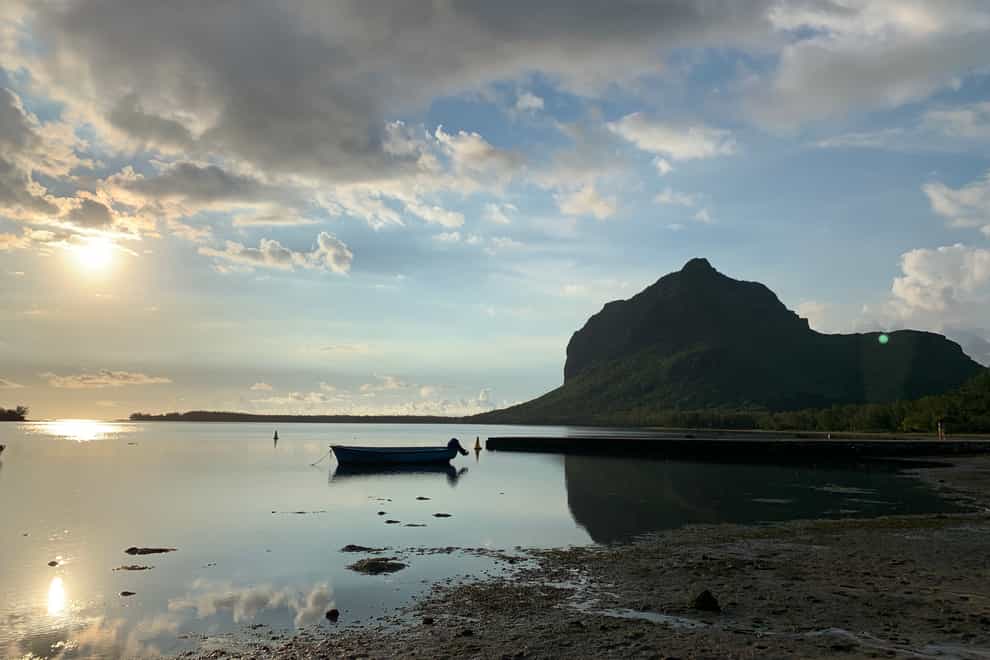The sun sets over the west coast of Mauritius, with one of its many mountains in the distance (Ryan Hooper/PA)