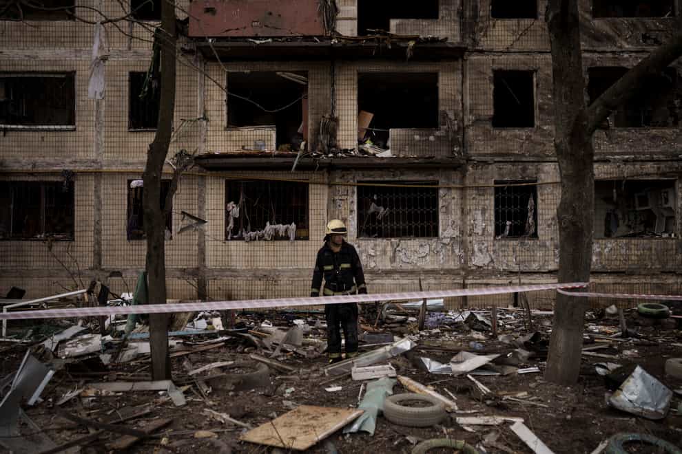 A Ukrainian firefighter walks outside a destroyed building after it was hit by artillery shelling in Kyiv in Ukraine on Monday March 14 2022 (Felipe Dana/AP)