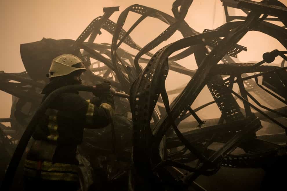 A Ukrainian firefighter extinguishes fire inside a large food products storage facility which was destroyed by an airstrike on the outskirts of Kyiv (Vadim Ghirda/AP)