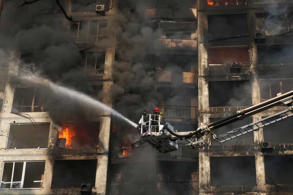 Firefighters work in an apartment building damaged by shelling in Kyiv (AP)