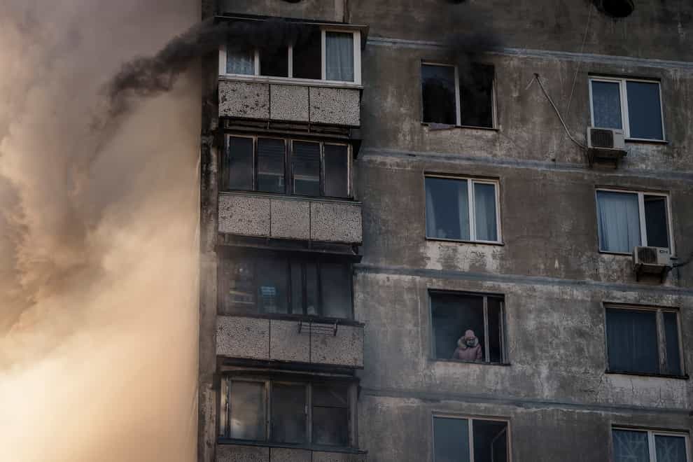 An elderly resident waits to be rescued by firefighters after an apartment building was hit by shelling in Kyiv (AP)
