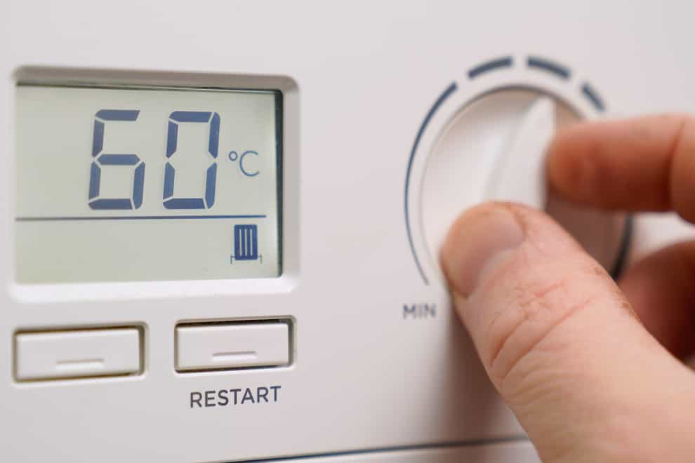 A homeowner turns down the temperature of a gas boiler (Andrew Matthews/PA)