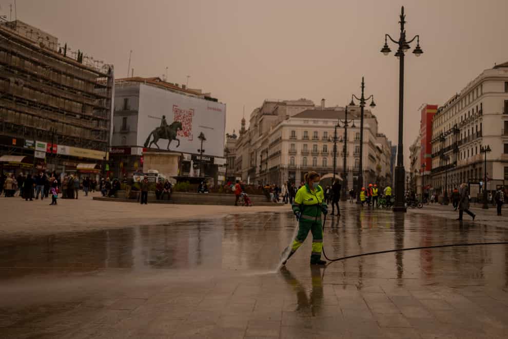 A worker cleans the dust from the Sahara desert in Sol square in Madrid, Spain (Manu Fernandez/AP)