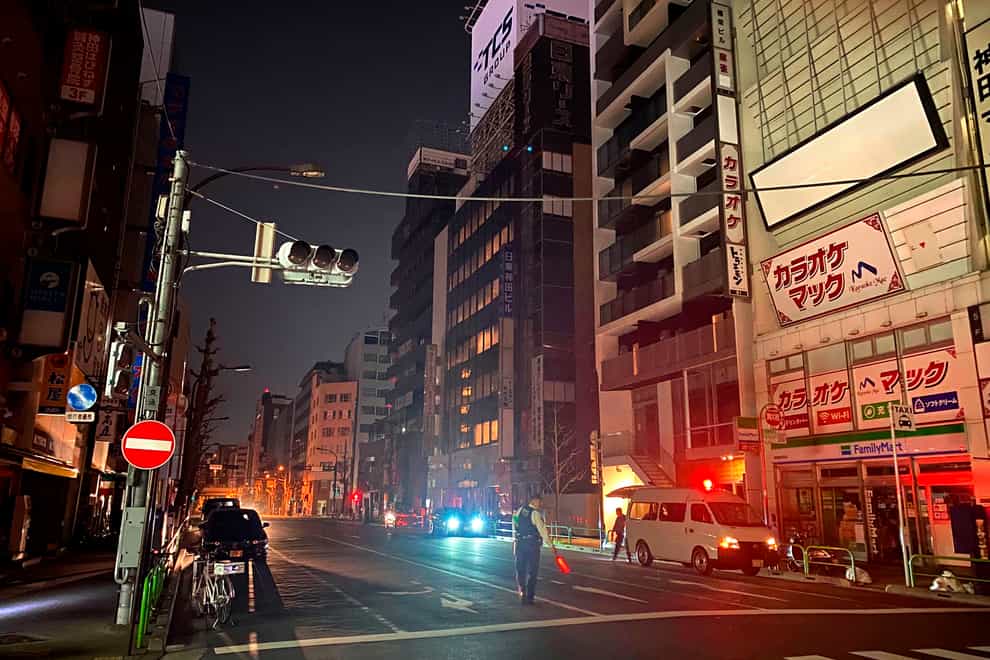 A policeman stands on a street during a blackout in Tokyo (Kyodo News via AP)